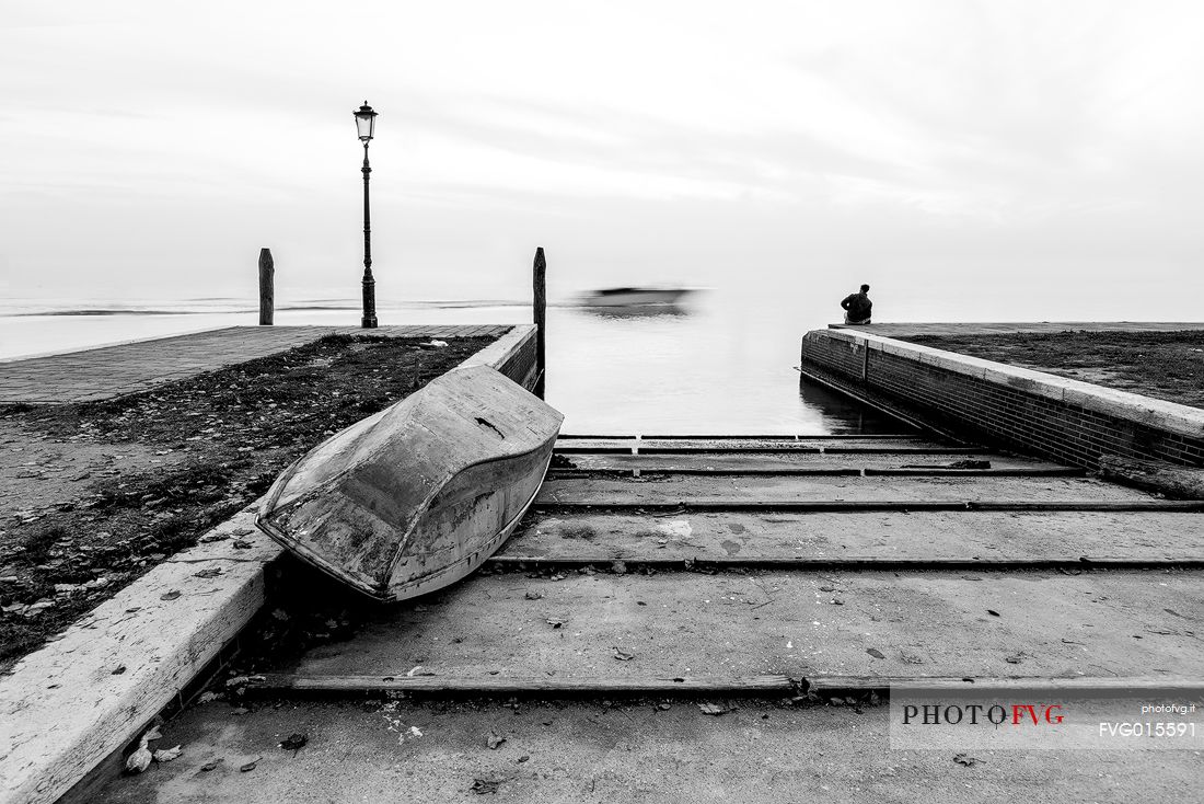 The man watches the passage of the boat in the Burano lagoon