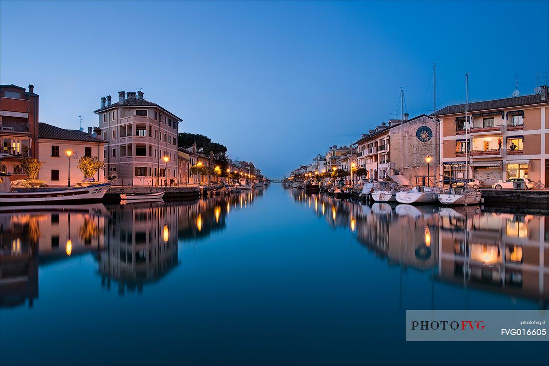 The port of Grado Vecchia is reflected in the lagoon at the blue hour