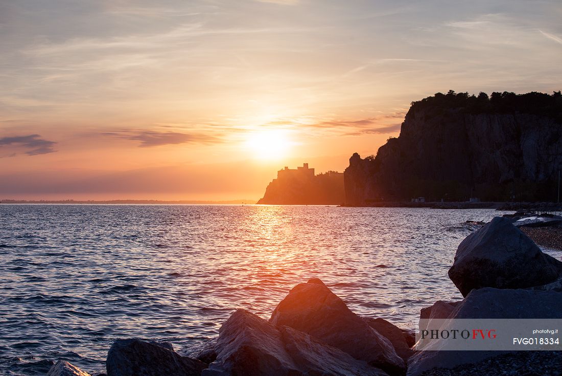 The Duino castle at sunset photographed from Porto Piccolo's beach in Sistiana