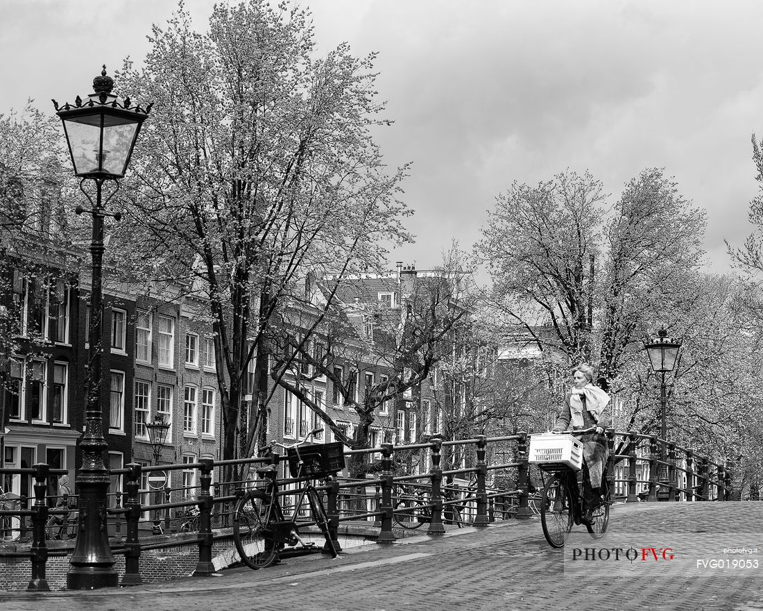Woman on bicycle along the Keizersgracht, one of the main canals of the historical center of Amsterdam