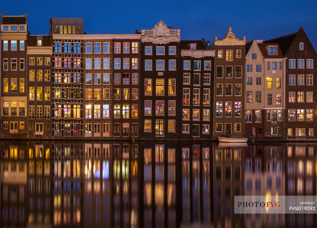 The lights of the houses are reflected on the Damrak canal in the center of Amsterdam