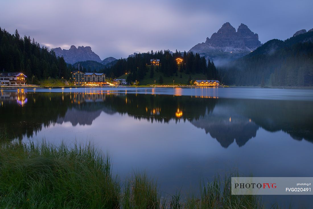 The evening lights illuminate the Lake Misurina with the Tre cime of Lavaredo in the background