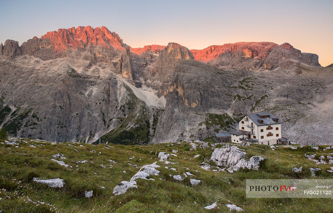 The alpine refuge Zsigmondy-Comici with Cima undici behind illuminated at sunset