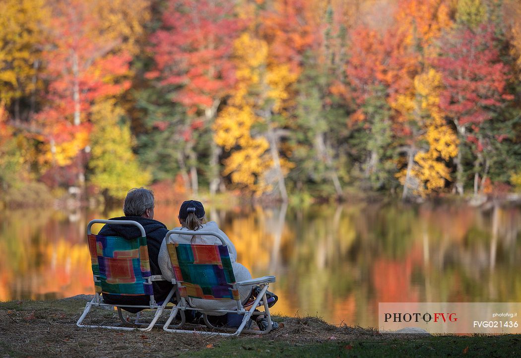 Two people admire the autumn colors reflected in the Echo lake in New Hampshire,United States of America