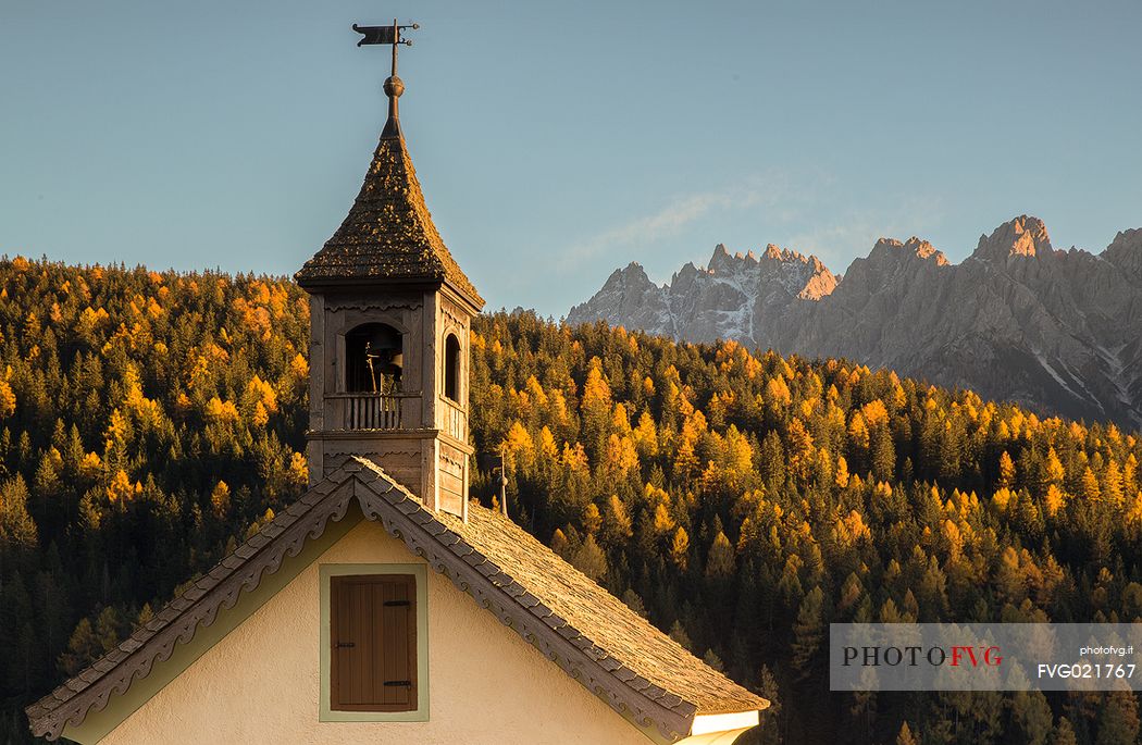 The little church of Dobbiaco and Baranci group on background during an autumn sunset