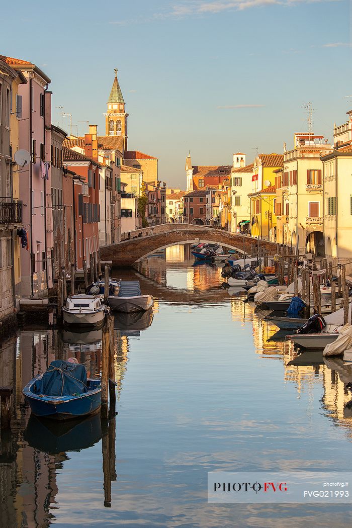Sunset on the Canal Vena, one of the most picturesque canals of Chioggia; in the background the church tower of St. James,  Italy