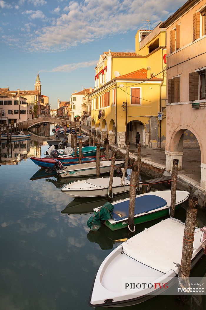 Sunset on the Canal Vena, one of the most picturesque canals of Chioggia; in the background the church tower of St. James, Italy
