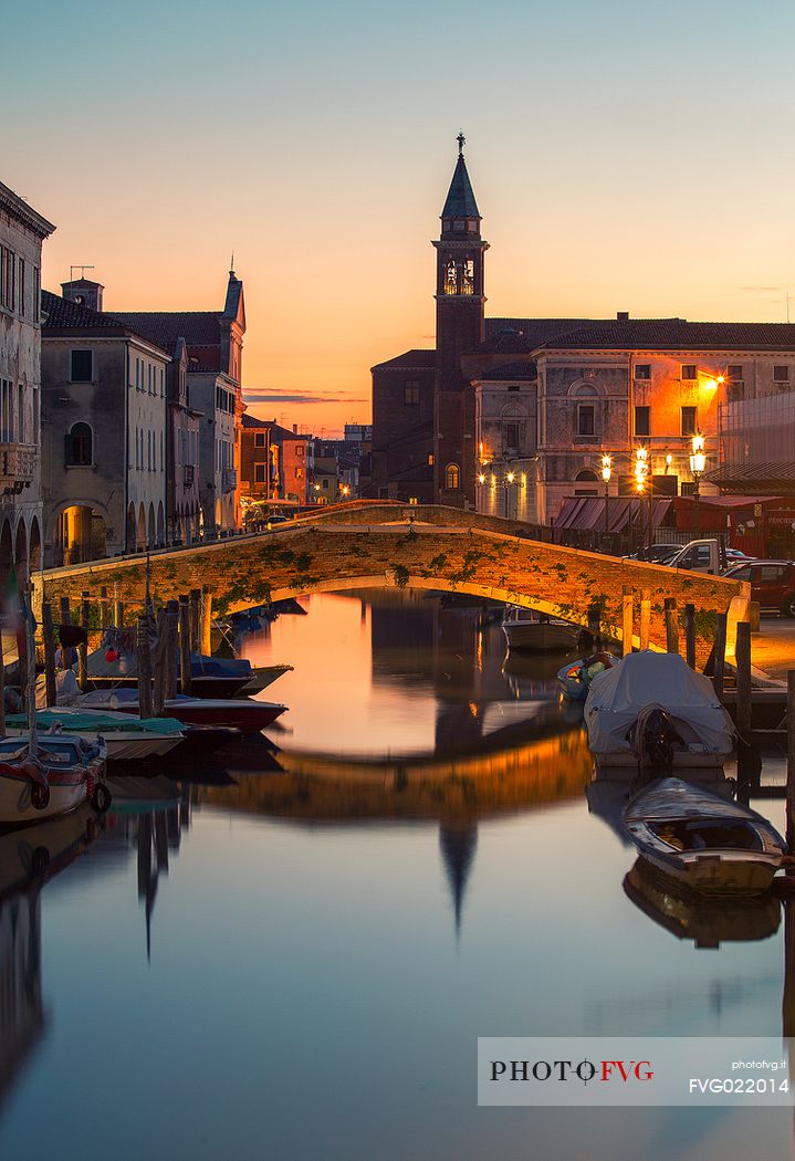 Sunset on the Canal Vena, one of the most picturesque canals of Chioggia; in the background the church tower of St. James, Chioggia, Italy