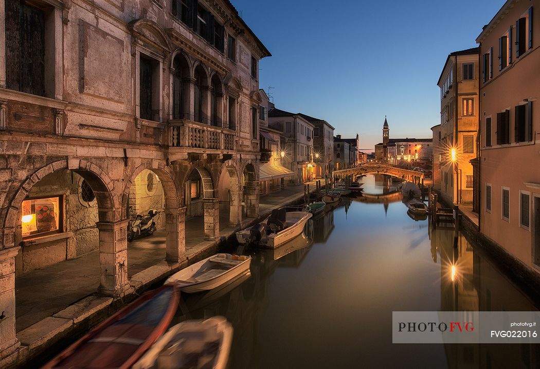 Canal Vena with the Palace Lisatti-Mascheroni in the foreground and the St. James church tower in the background during the blue hour, Chioggia, Italy