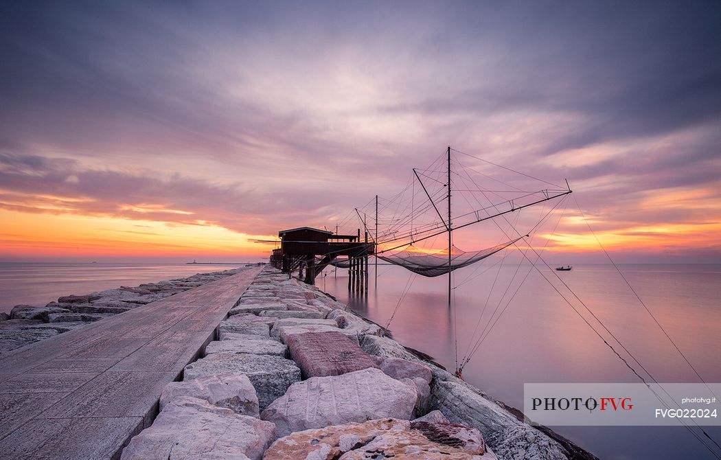 Stilt fishermen on the sea at the dam of Sottomarina during the sunrise, Chioggia, venetian lagoon, Italy