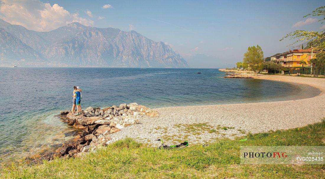 A couple embraces on a beach of Malcesine on Lake Garda, Italy