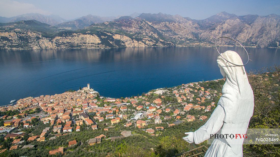 The statue of the Madonna dell'Accoglienza dominates the small medieval village of Malcesine on Garda lake, Italy