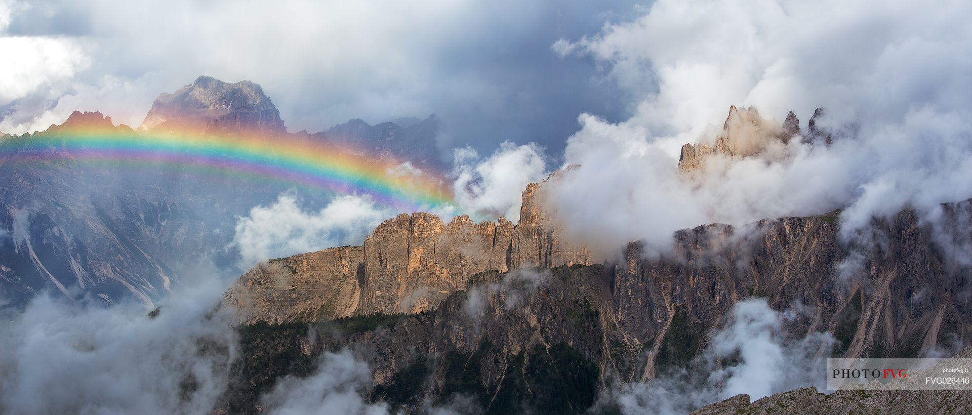 An intense rainbow stands out in front of the Sorapis after a strong thunderstorm with the Croda Da Lago wrapped in the clouds in the foreground, Dolomites, Cortina D'Ampezzo, Italy