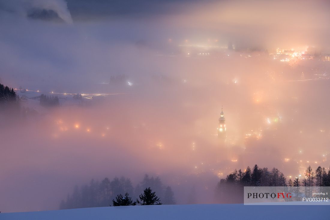 Dobbiaco village in the fog at twilight, Pusteria valley, dolomites, Trentino Alto Adige, Italy, Europe
