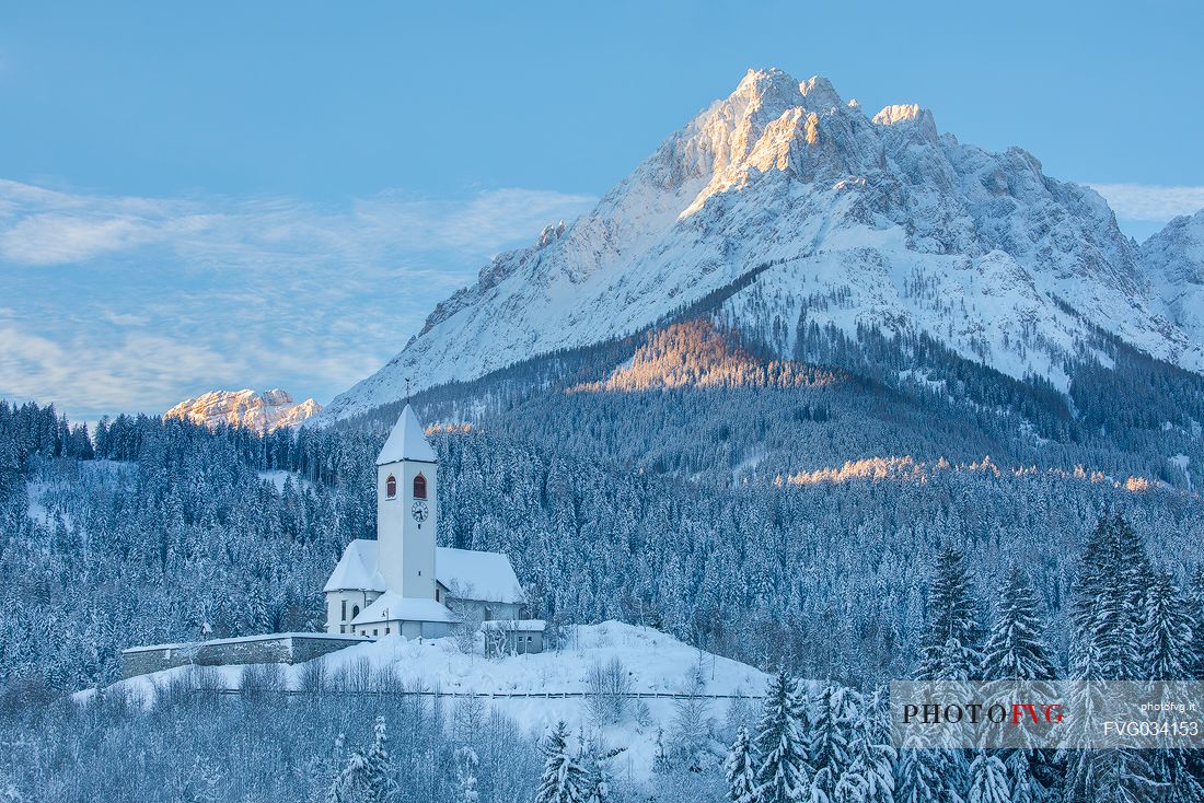 The church of the village of Versciaco after an intense snowfall, in the background the Rocca dei Baranci peak illuminated at dawn, Innichen, dolomites, Pusteria valley, Trentino Alto Adige, Italy, Europe