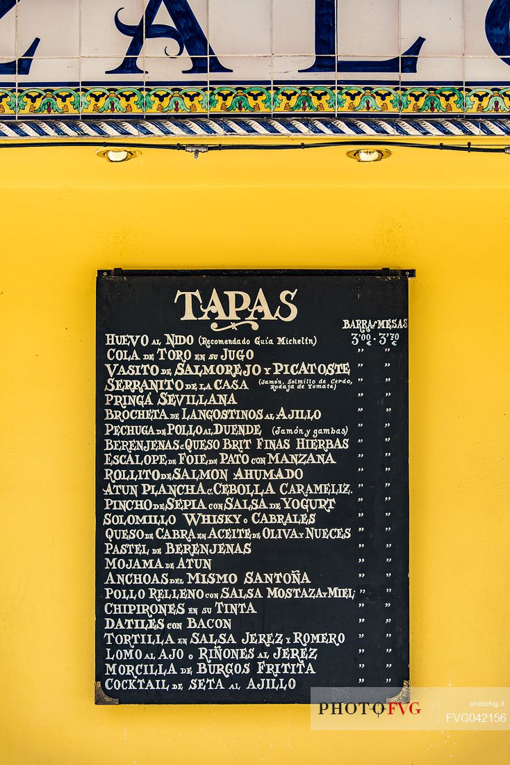 Tapas menu, typical Spanish food displayed outside a bar in the Barrio de Santa Cruz, Seville, Andalusia, Spain, Europe