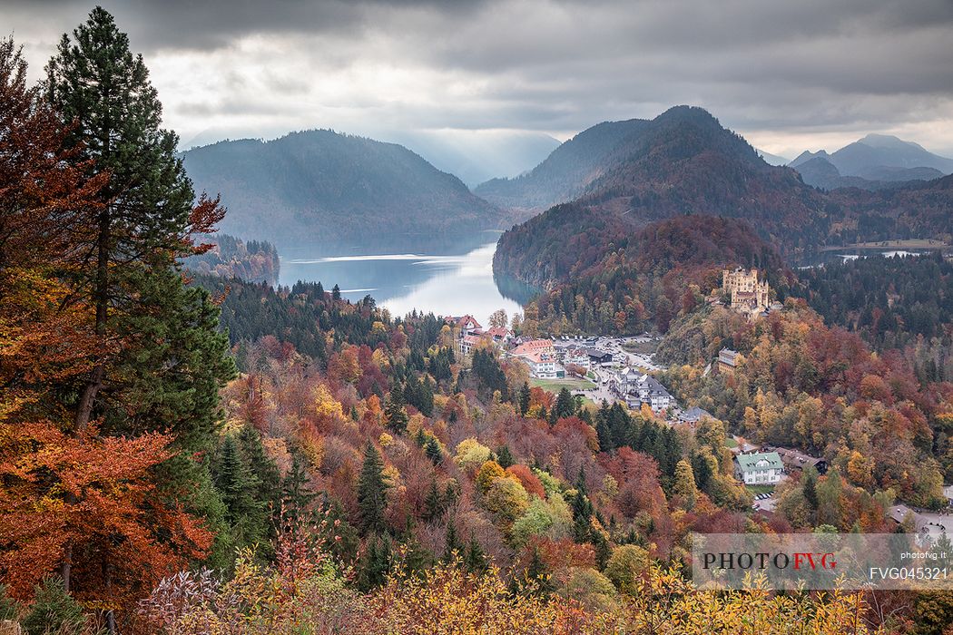 The Hohenschwangau castle, Schloss Hohenschwangau, with lake Alpsee and Tannheim Mountains, Schwangau near Fuessen, surrounded by autumn colors, Bayern, Germany, Europe