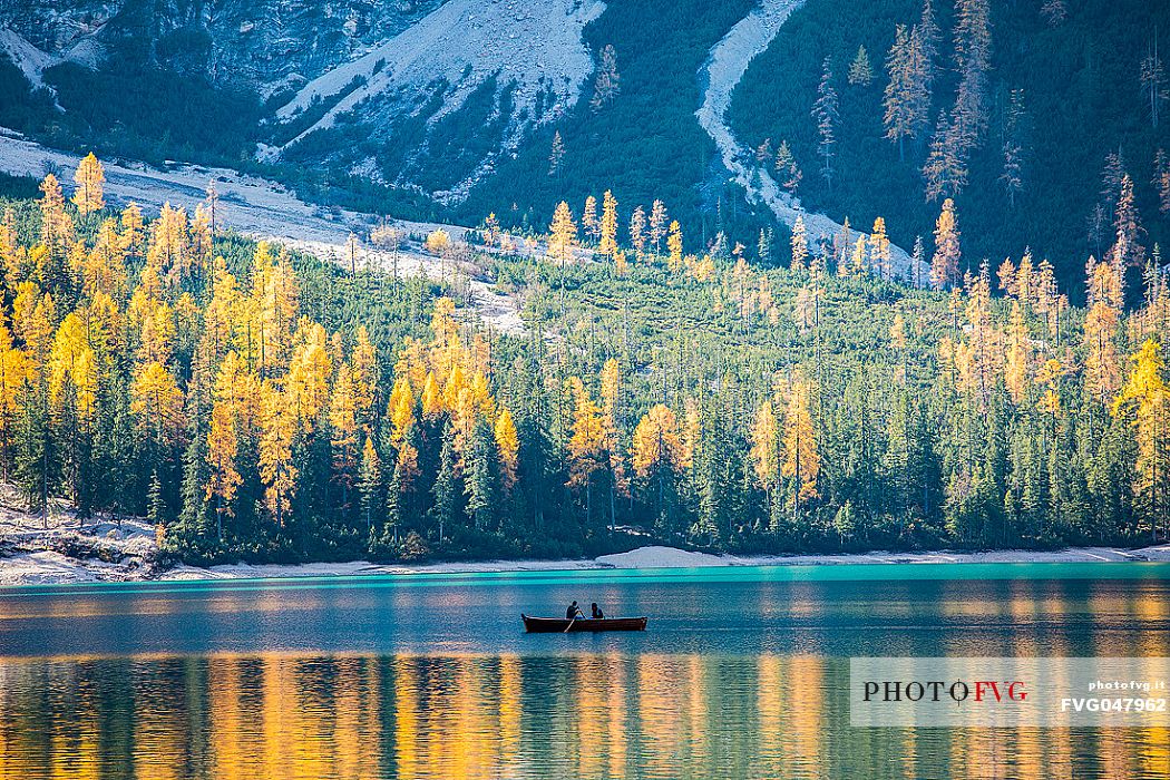 Pair of tourists in a boat on Lake Braies with autumn colors, dolomites, Pusteria valley, Trentino Alto Adige, South Tyrol, Italy, Europe