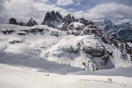 Hikers along the path to Auronzo Refuge, in the background the mountain group of Cadini di Misurina