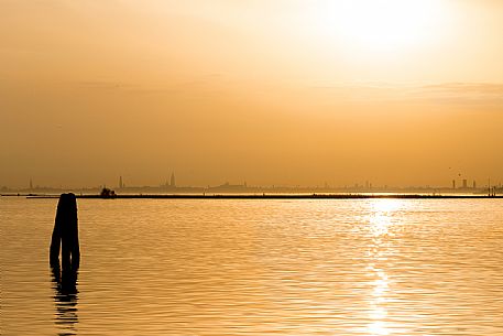 Gold and soft sunset from Burano towards Venice with the Basilica of St Giorgio Maggiore on background