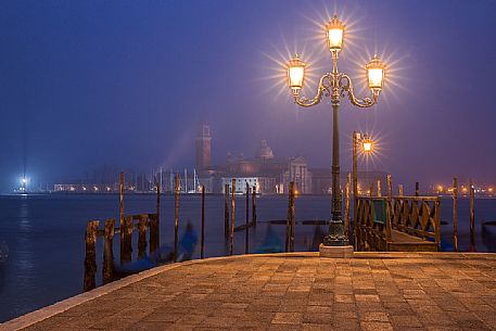 Evening's lights on the gondolas in St. Mark's basin in Venice, in the background the Basilica of Saint Giorgio Maggiore.