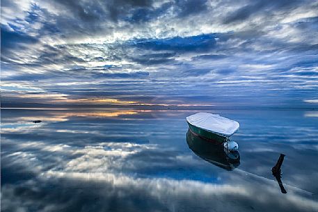 Reflections of an overcast summer sunrise on the lagoon of Grado