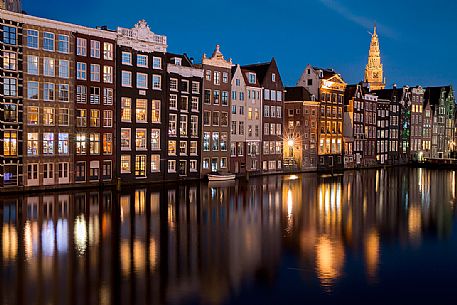 The lights of the houses are reflected on the Damrak canal in the center of Amsterdam