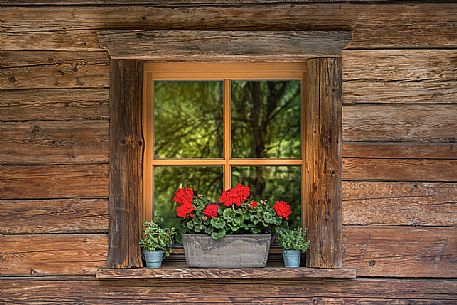 Window of a wooden cottage in Sesto, dolomites, Itay