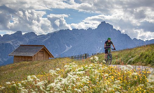 Cyclist on the Elmo mount paths with Cima Tre Scarperi and Sesto peaks in the background