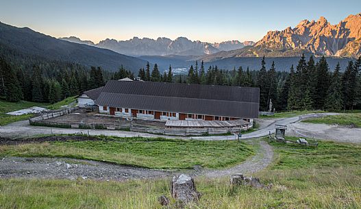 Coltrondo hut with Sesto Dolomites lit at dawn and the Comelico Dolomites on background