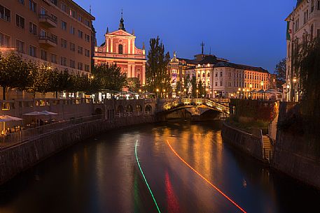 The night skies of a boat along the river Ljubljanica, in the background the triple Bridge or Tromostovje bridge, the Franciscan church and the palaces in the center of Lubiana, Slovenia, Europe