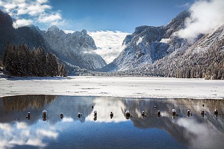 The dolomites are reflected on the Dobbiaco lake (Toblacher See) in a winter morning, Pusteria valley, Italy