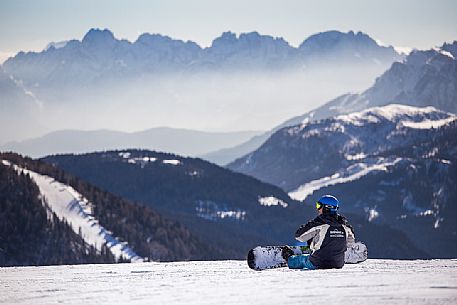 Snowboarder takes a break in front of the Comelico Dolomites, Sexten, Italy Snowboarder takes a break in front of the Comelico Dolomites, Sexten, Italy