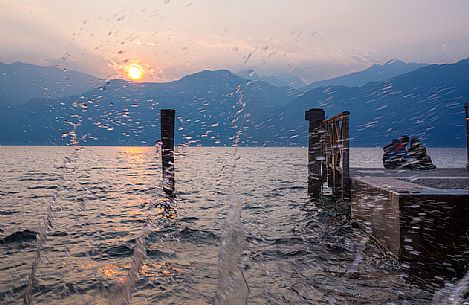 The waves of Lake Garda crash on the shore during a romantic sunset at Malcesine, Italy The waves of Lake Garda crash on the shore during a romantic sunset at Malcesine, Italy