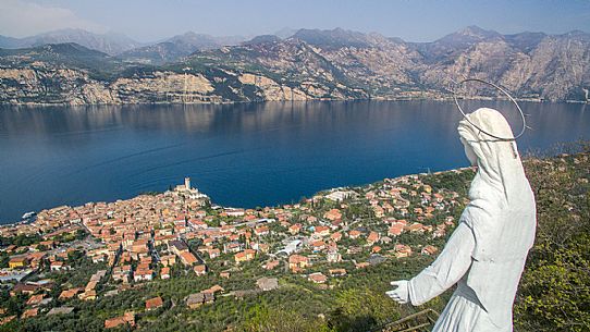 The statue of the Madonna dell'Accoglienza dominates the small medieval village of Malcesine on Garda lake, Italy