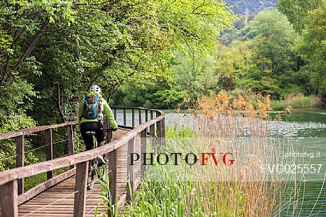 Cyclist along the catwalk of the Toblino lake, Valley of Lakes, Trentino, Italy 