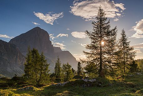 The morning sun illuminates the meadows at Passo Falzarego, in the background the Tofana di Rozes, Cortina D'Ampezzo, Dolomites, Italy