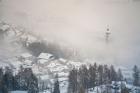 The bell tower of the church of Dobbiaco appears from above the clouds, Pusteria valley, dolomites, Trentino Alto Adige, Italy, Europe