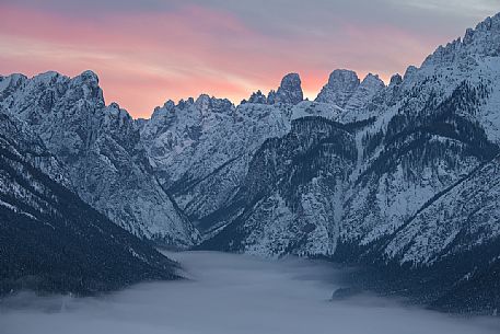 The peaks above the village of Dobbiaco covered by low clouds, in the background  Cristallo and Piz Popena mount, Pusteria valley, dolomites, Trentino Alto Adige, Italy, Europe