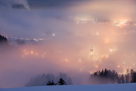 Dobbiaco village in the fog at twilight, Pusteria valley, dolomites, Trentino Alto Adige, Italy, Europe
