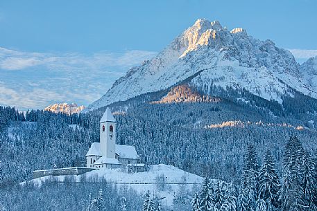 The church of the village of Versciaco after an intense snowfall, in the background the Rocca dei Baranci peak illuminated at dawn, Innichen, dolomites, Pusteria valley, Trentino Alto Adige, Italy, Europe