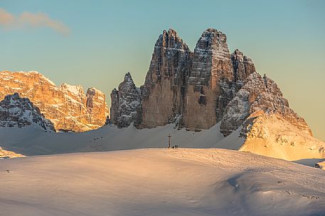 The summit cross of the Specie Mount and the Tre Cime di Lavaredo on background at sunset, Prato Piazza, Braies, Trentino Alto Adige, Italy