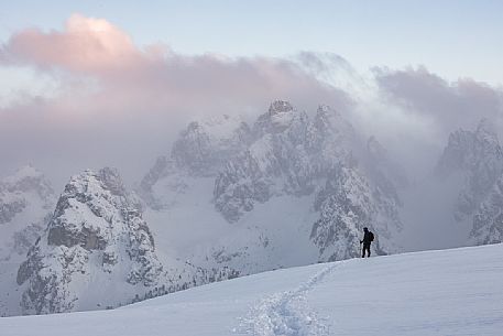 Hiker on the path to Monte Piana, in the background the clouds envelop the peaks of Cadini di Misurina, dolomites, Auronzo di Cadore, Veneto, Italy, Europe