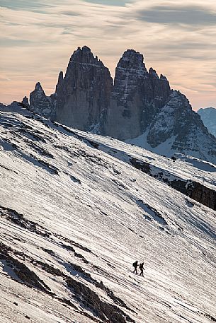 Hikers descend the mountain path to Prato Piazza, on background the Tre Cime di Lavaredo peak, Fanes Senes Braies Natural Park, Pustertal, dolomites, South Tyrol, Italy, Europe