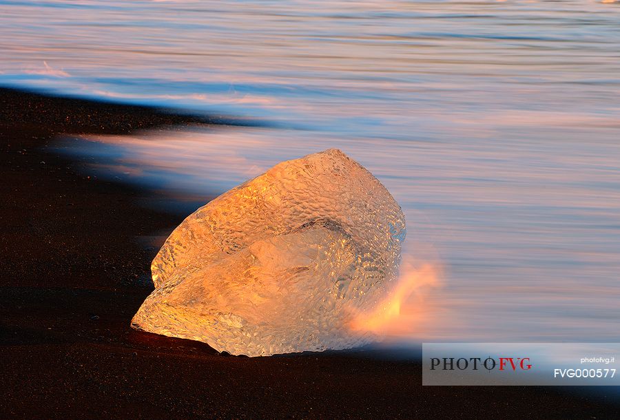 A little piece of ice becomes like gold thanks to the warm light of the sunrise