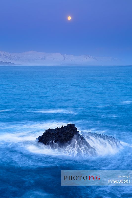 The rising moon frames a seascape whose shades are wintry