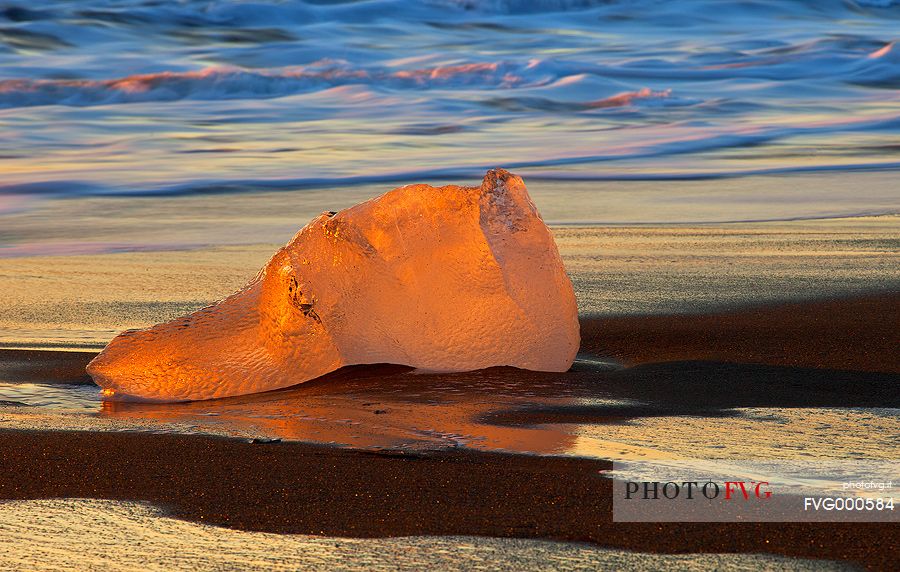 A big block of stranded ice
on the volcanic beach of Jokulsarlon becomes a spectator to a special sunrise