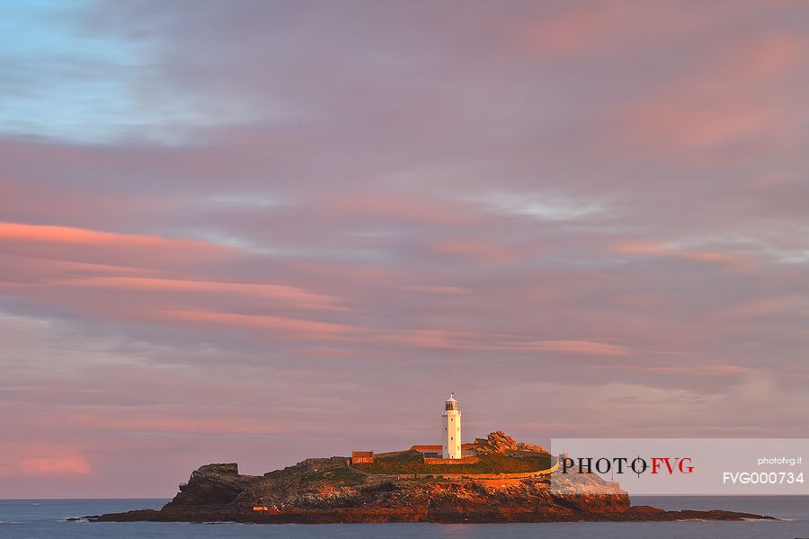 Sunrise colours and rainbow over Godrevy Lighthouse