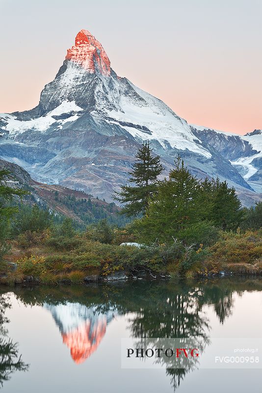 The first light of dawn strikes the top of the Matterhorn which in turn is reflected in the waters of Grindjisee