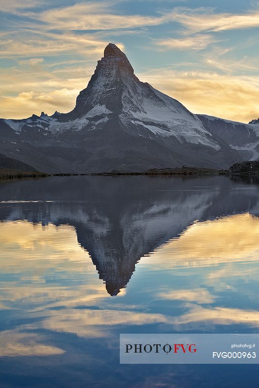 The great summit of the Matterhorn with its beautiful shape, emerges from the water during sunset of Stellisee